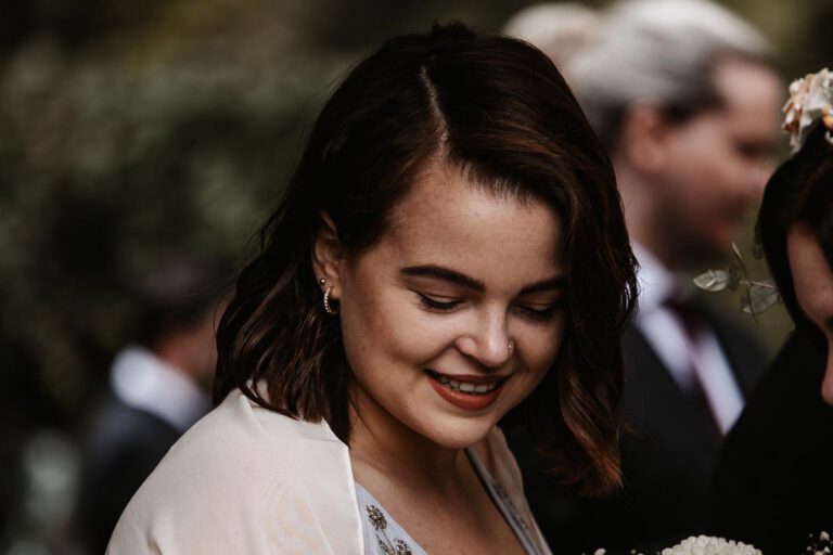 Ein weiblicher Gast auf einer Hochzeit in Murnau, die sich für das Brautpaar freut, aufgenommen in Farbe