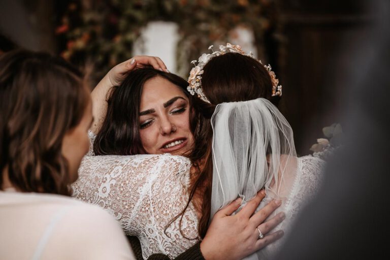 Der Braut wird nach der Trauung gratuliert, beide haben die Augen geschlossen, sie umarmen sich. Die Hochzeit war in Murnau