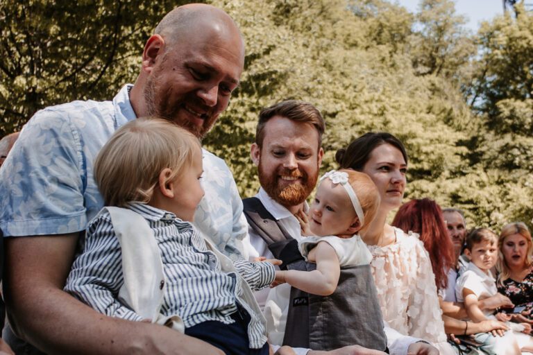 Ein Kind lächelt einem anderen Kind zu, es ist ein schöner Sommertag auf der Hochzeit in Solingen, die Gäste lachen sich an