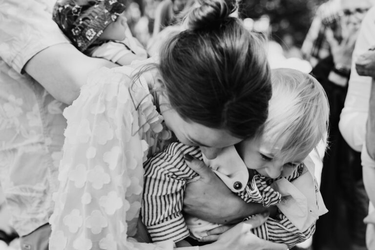 Ein schwarzweiß Foto von einer jungen Frau, die ein Kind auf einer Hochzeit vor lauter Glück umarmt