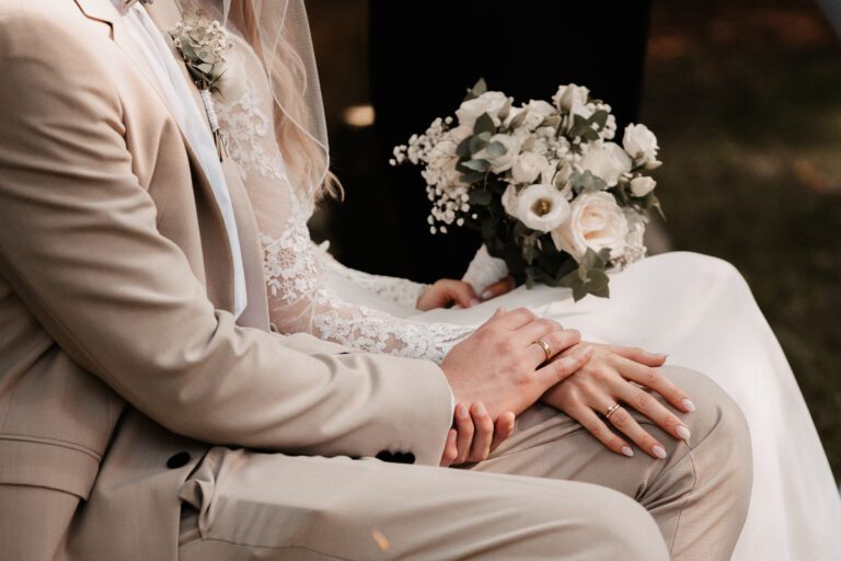 Brautpaar hält sich während der Trauung an den Händen, aufgenommen in Garmisch-Partenkirchen in Farbe, sie halten einen Blumenstrauß