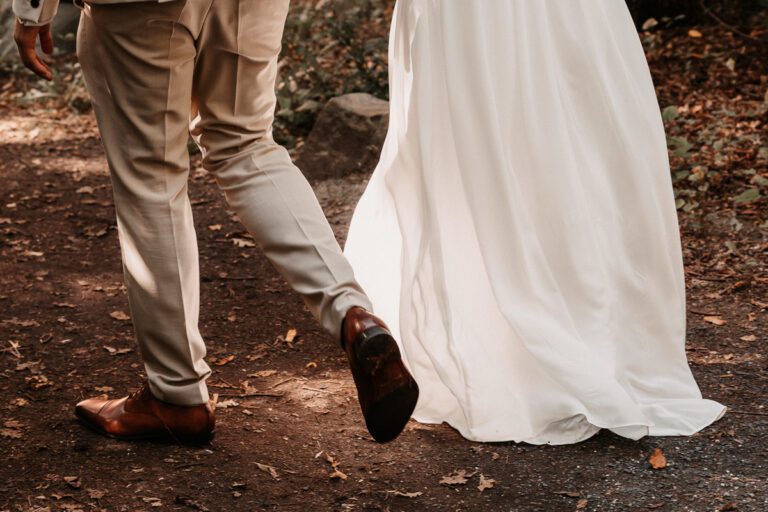 Das Brautpaar geht nach der Trauung in Richtung Fotoshooting, man sieht die Schuhe des Bräutigams und den Rock der Braut im Sonnenlicht, aufgenommen in Garmisch-Partenkirchen