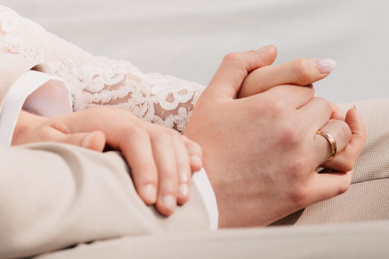 Eure Hochzeitsfotografin in Garmisch-Partenkirchen. Zwei Hände eines Brautpaares, das sich während der Trauung festhält, man sieht den Ehering, aufgenommen in Farbe