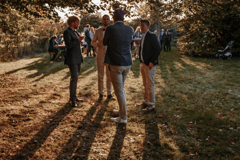Man sieht eine Gruppe Gäste auf einer Hochzeit in Garmisch-Partenkirchen im Sonnenuntergang, das Bild ist in Farbe aufgenommen, die Sonne steht tief und die Schatten der Personen sind auf dem Bild zu sehen